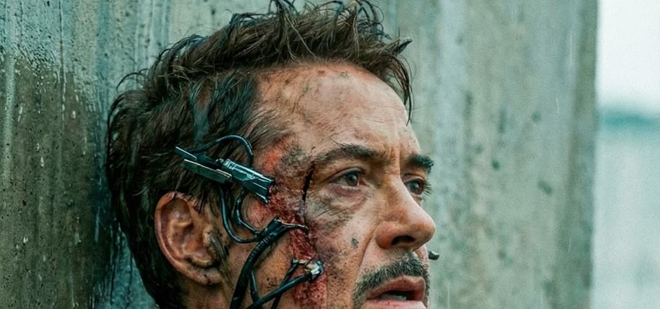 Iron Man in scorched Mark 85 armour, gauntlet raised, kneeling amid battlefield wreckage and smoke